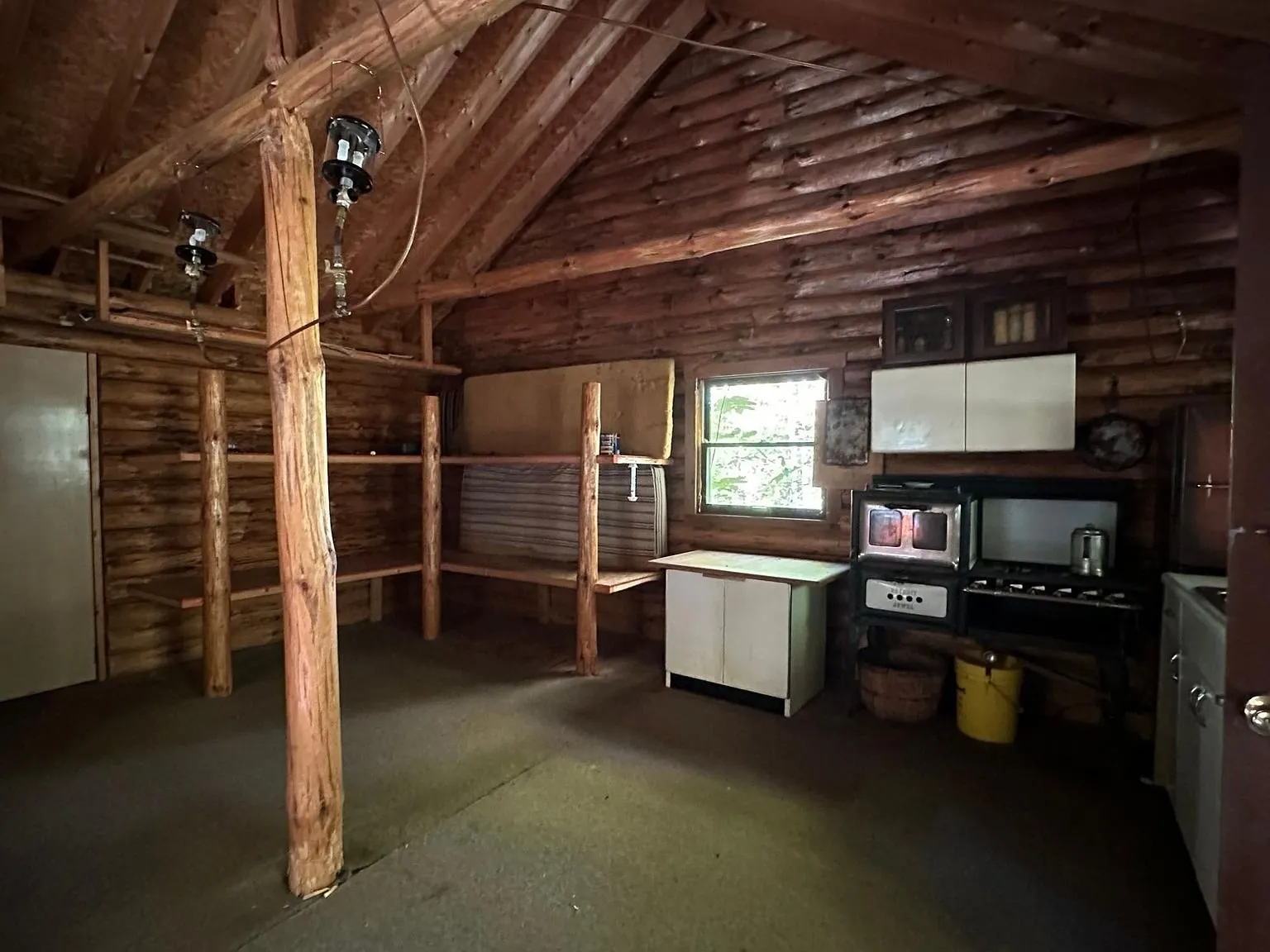 The kitchen counter, microwave and cabinets under the log roof