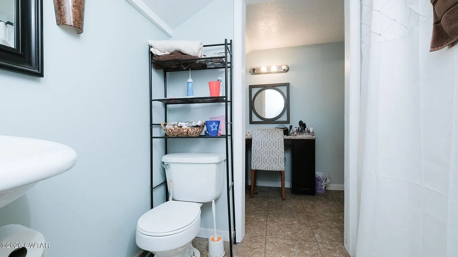 The second bathroom with the toilet and a shelf unit