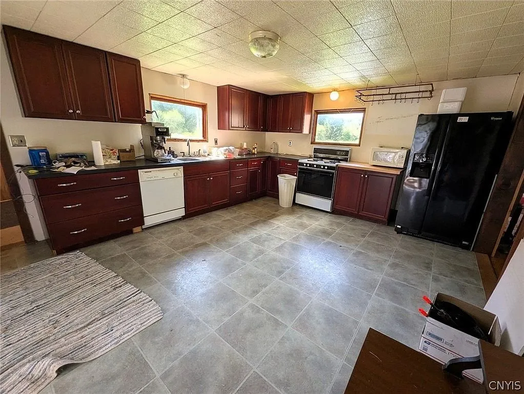 The kitchen with cherry cabinets, the white appliances and the tile floor