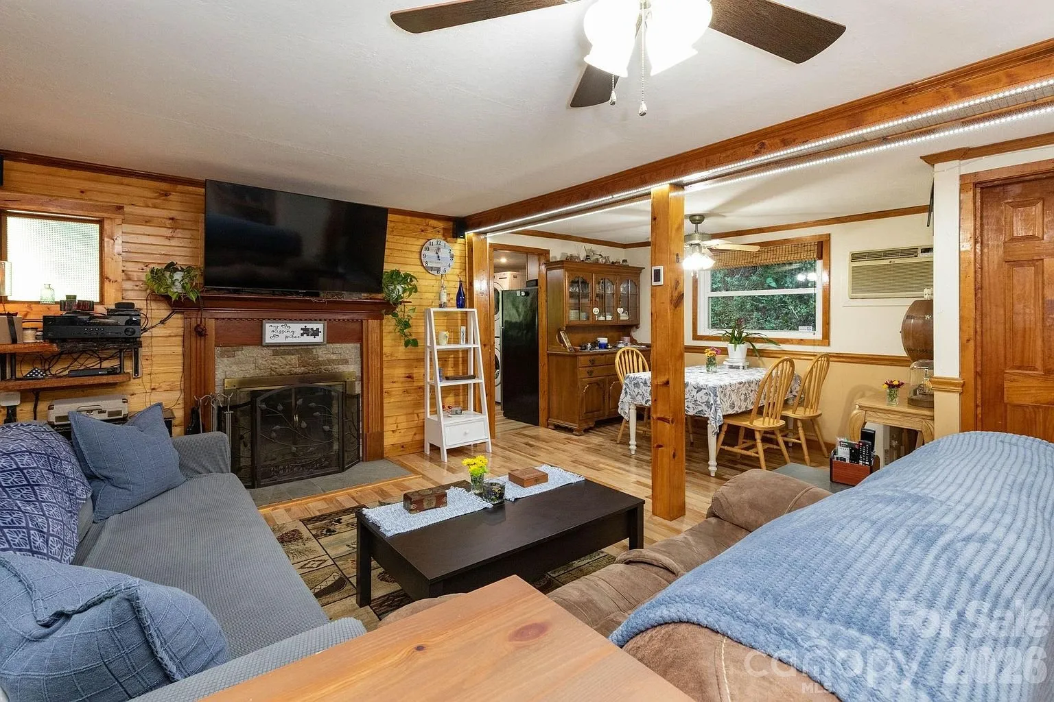 The living room with the sofas, the stone fireplace and the dining table beyond