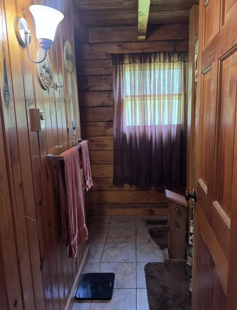 The hall with the tiled floor, the window and the towels on the rail