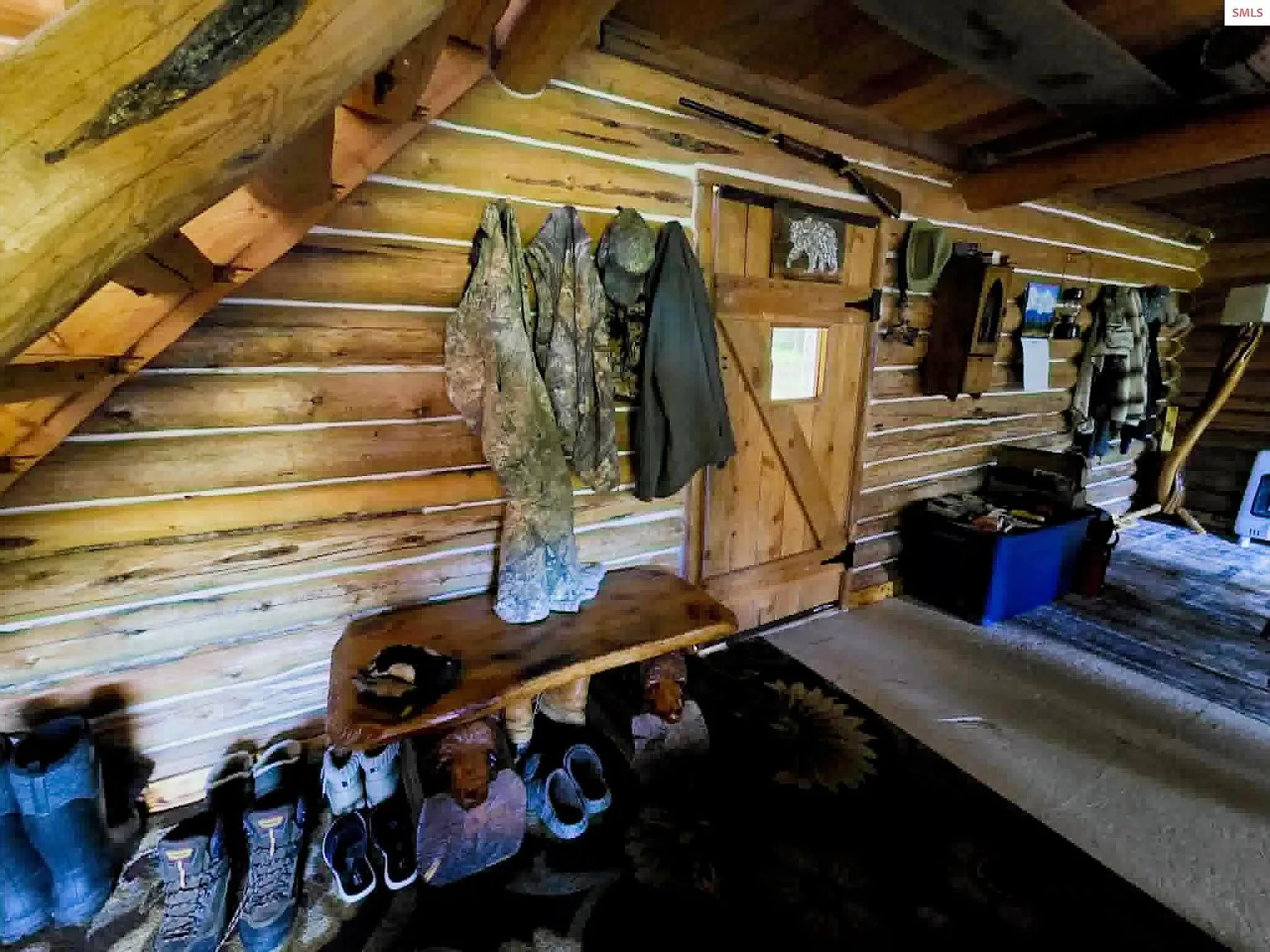 A mudroom area with hanging coats, boots and gear along the log wall