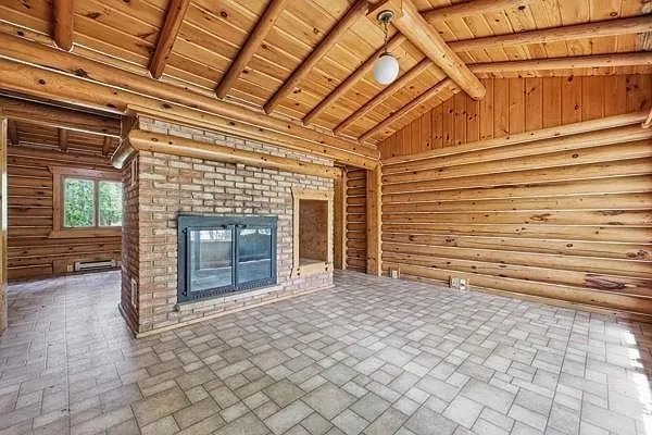 The main room with the brick double-sided fireplace and the log walls