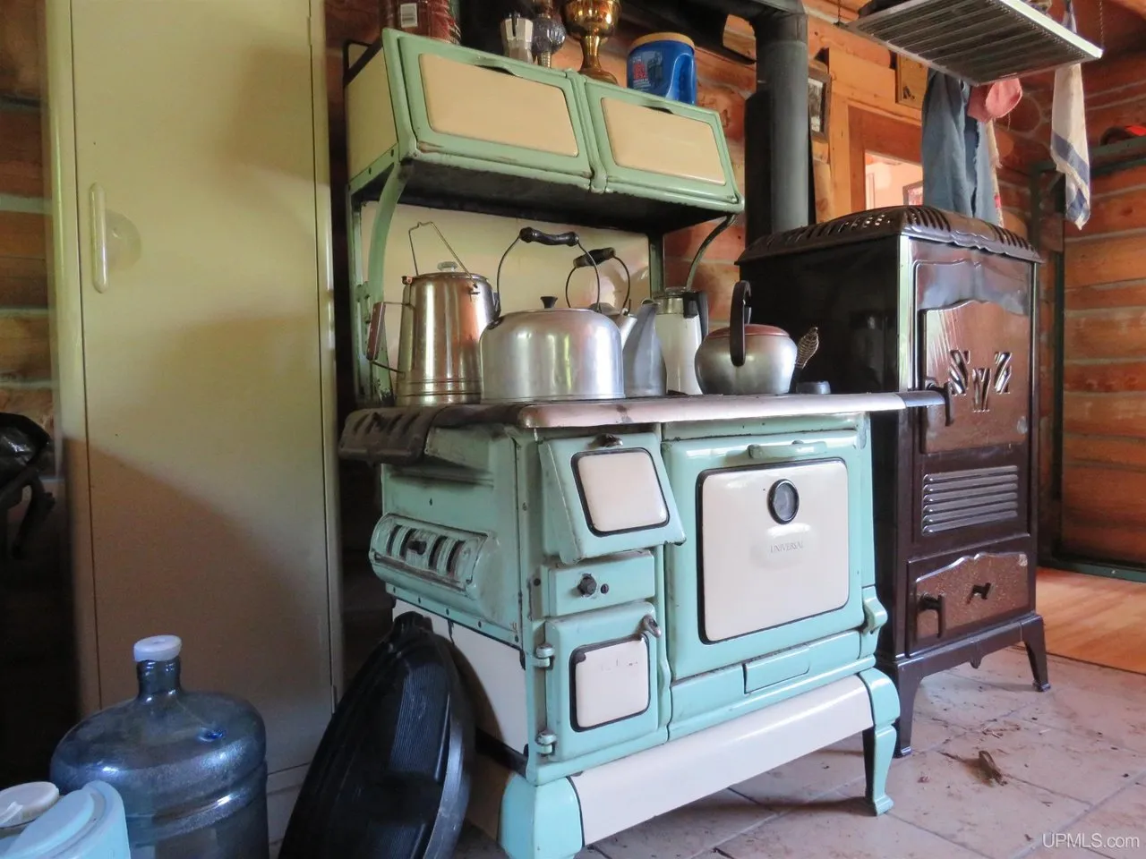 The wood cookstove with a kettle on top and water jugs beside it