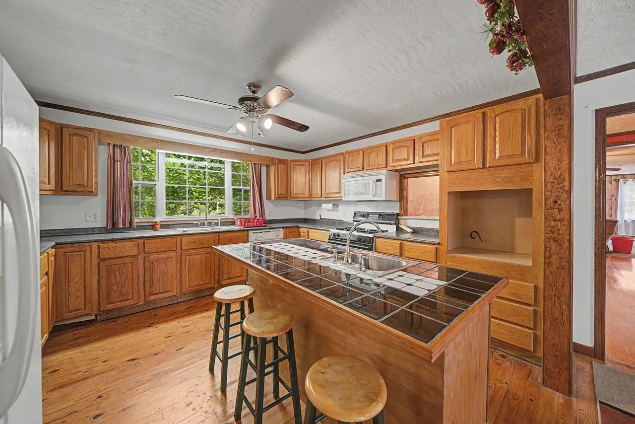 The kitchen with wood cabinets, an island and a window over the sink