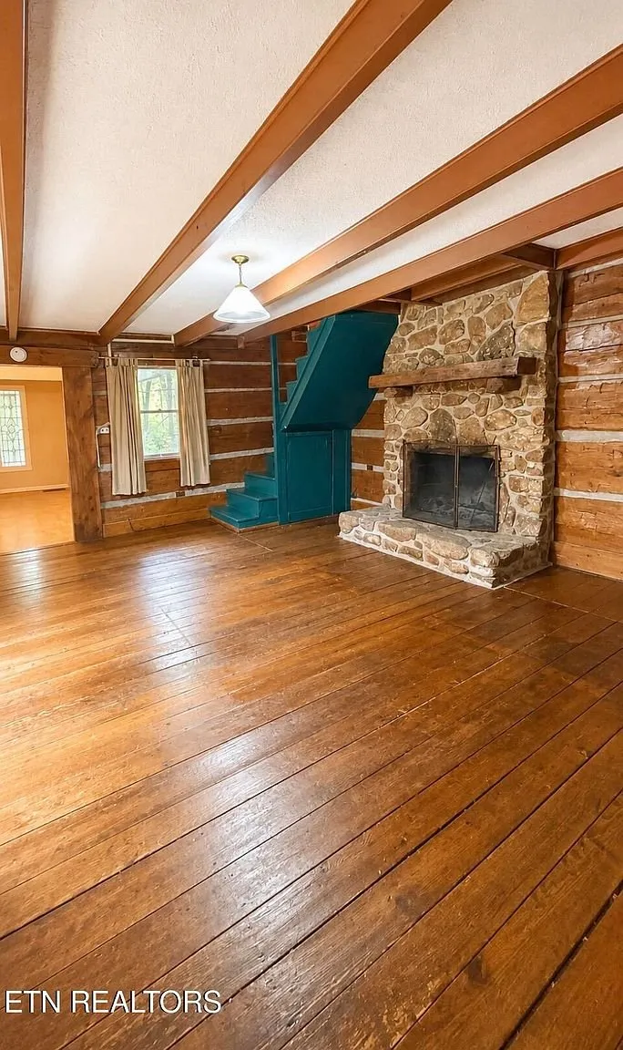 The log room with the stone fireplace and the teal boxed stair