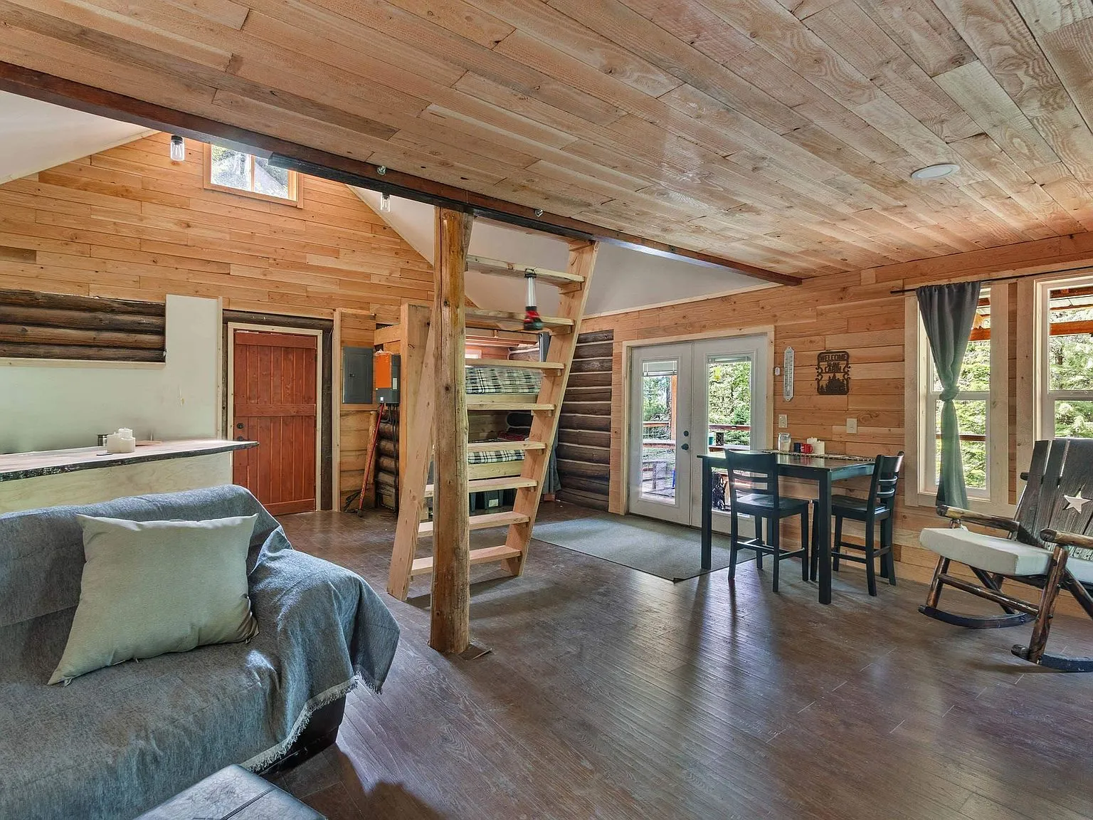 A made bed in the upstairs loft, tucked under the cabin's sloped log ceiling