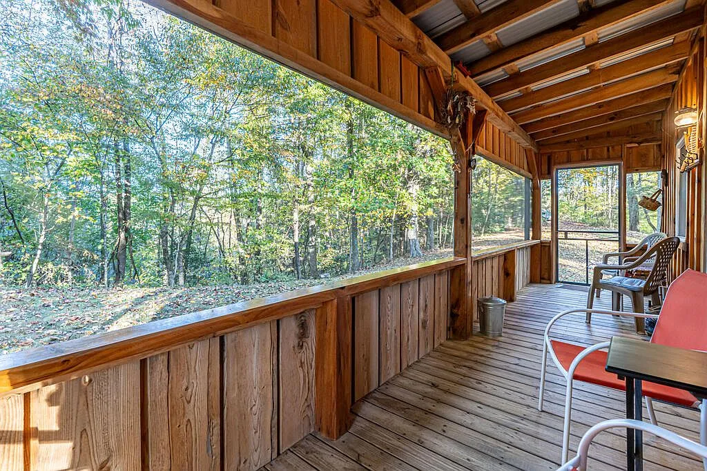 The screened porch's open rail view looking out over the wooded hillside
