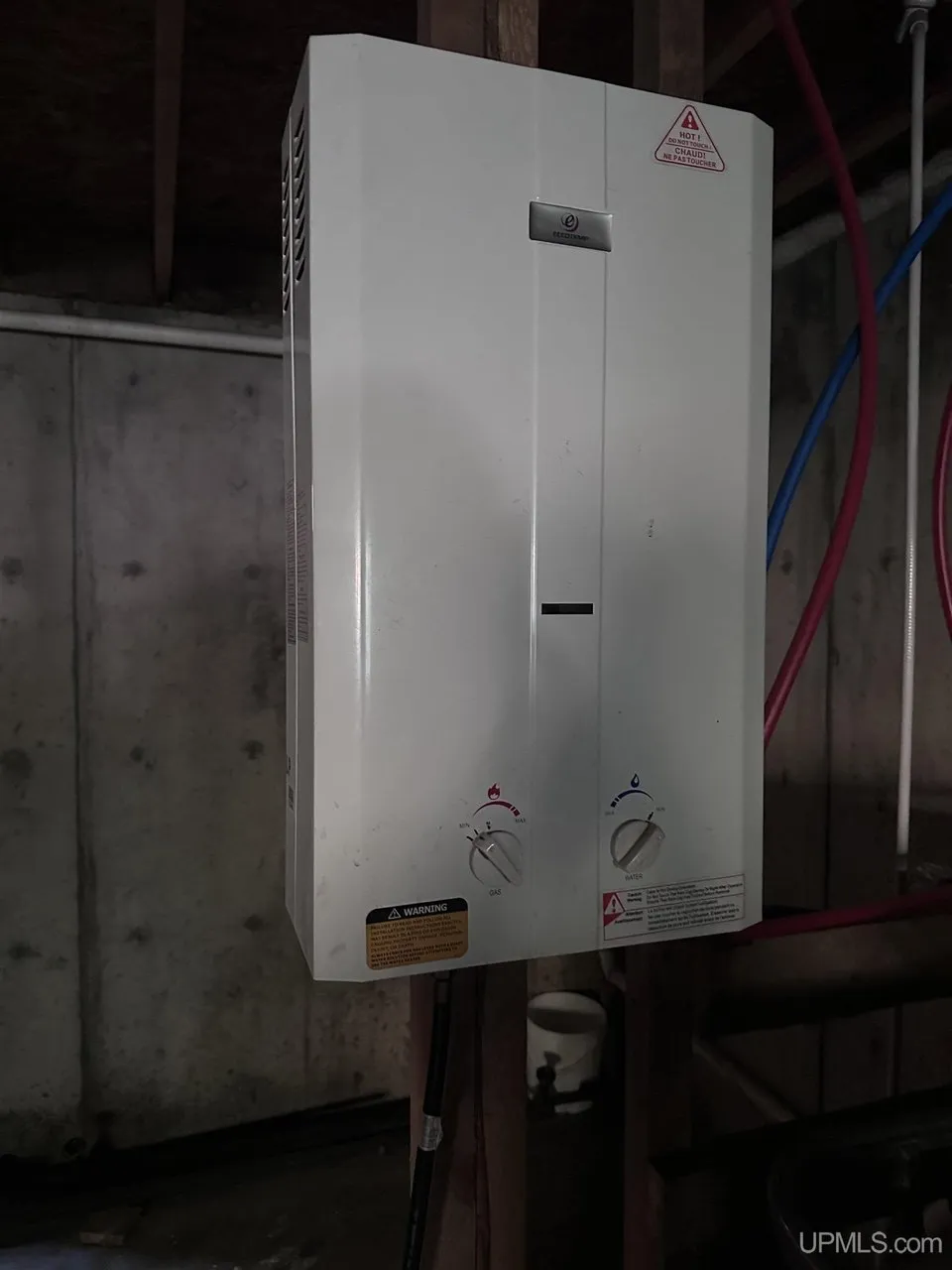 The tankless water heater on the basement wall