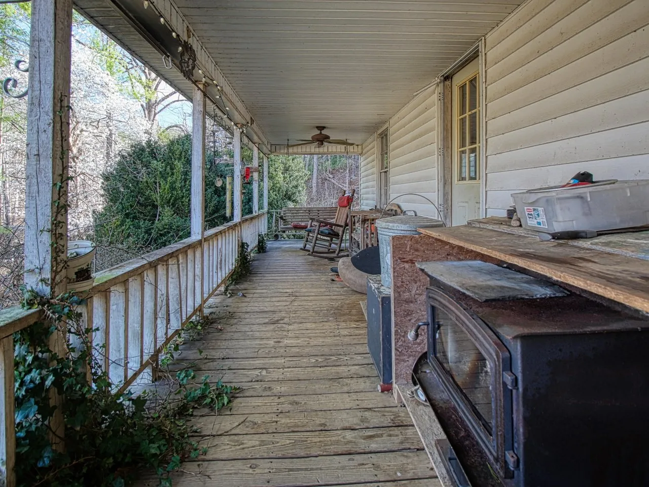 The covered front porch with a wood stove and stacked firewood at one end