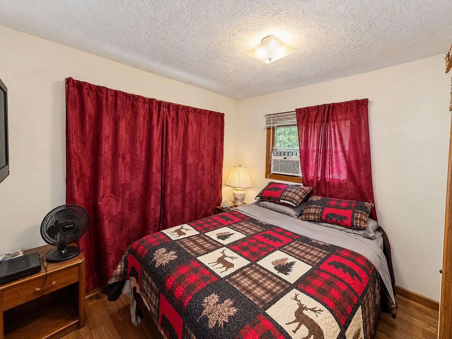 A bedroom with the bed, the red curtains and the fan