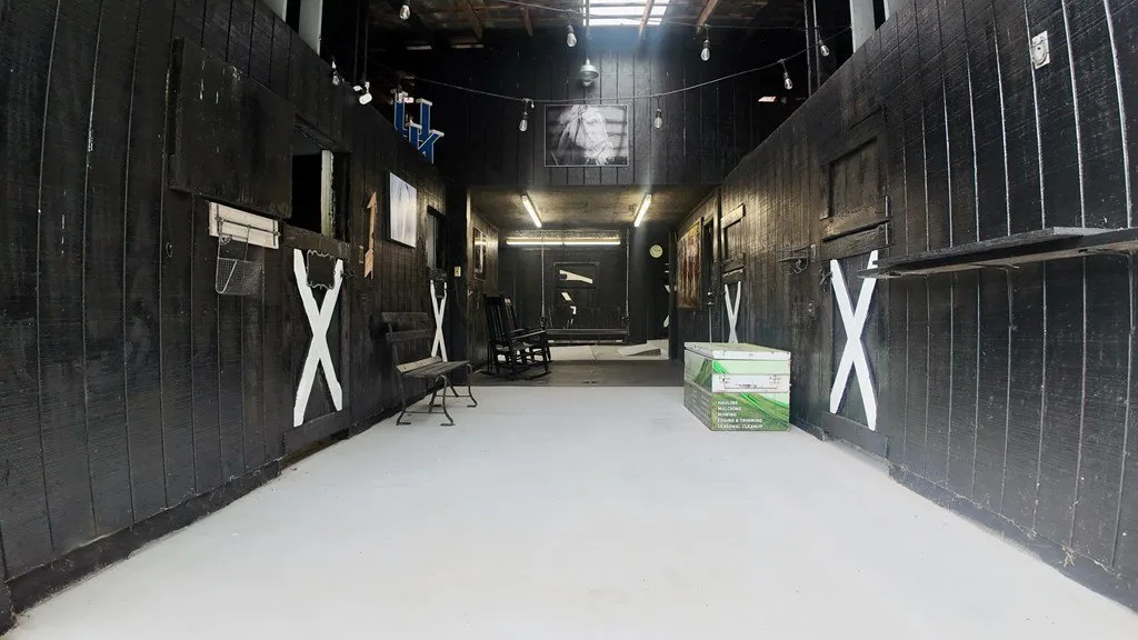 Inside the barn: black walls, white cross detailing and a concrete floor