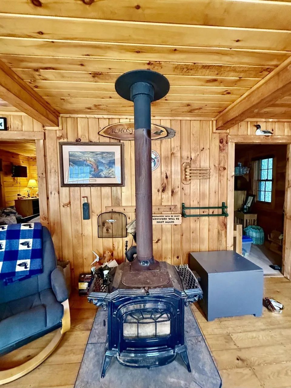 The wood stove on its hearth in the pine-paneled room