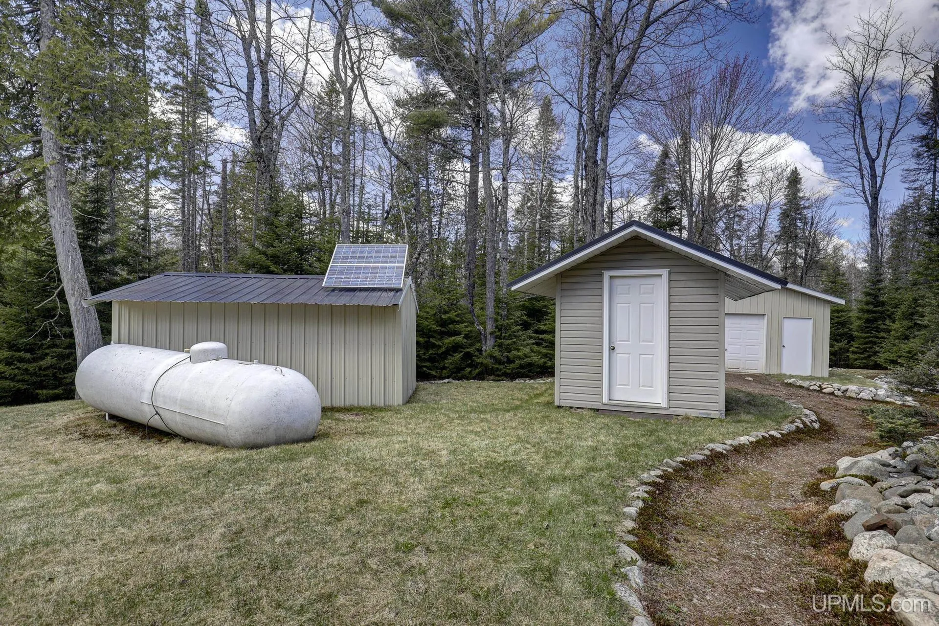 The propane tank beside the storage shed and a second shed