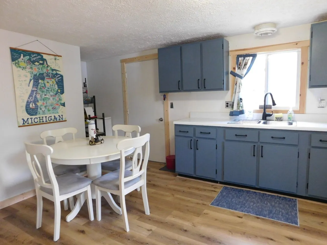 The dining table by the window with the kitchen behind