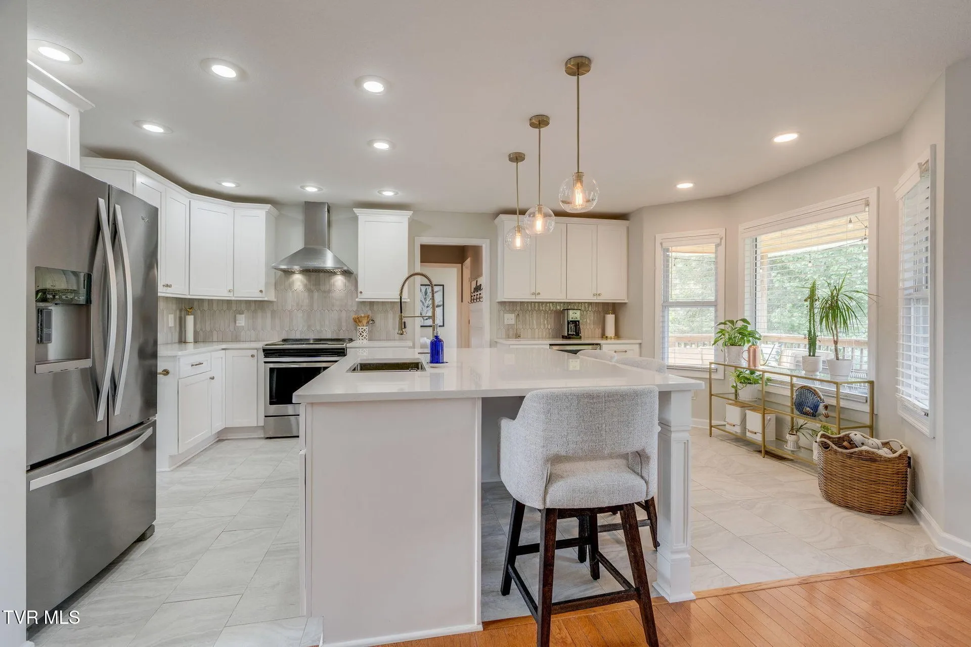 The kitchen with the quartz island, stainless refrigerator and pendant lights