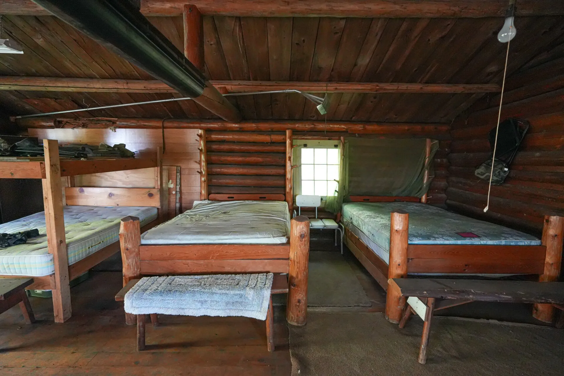 The bunk room with bare mattresses and log walls