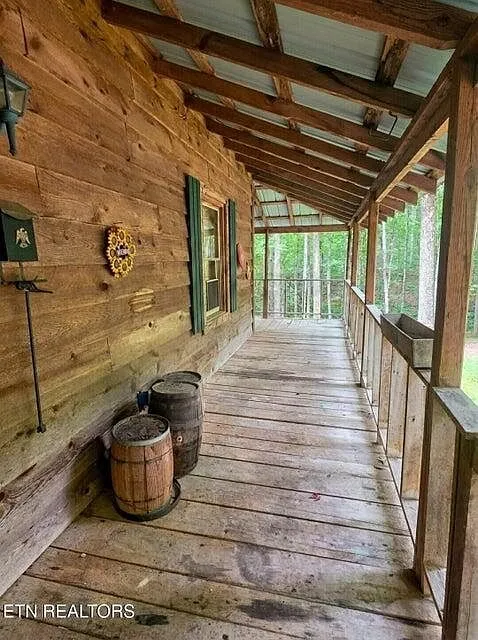 The side porch with wooden barrels set against the cabin's log exterior