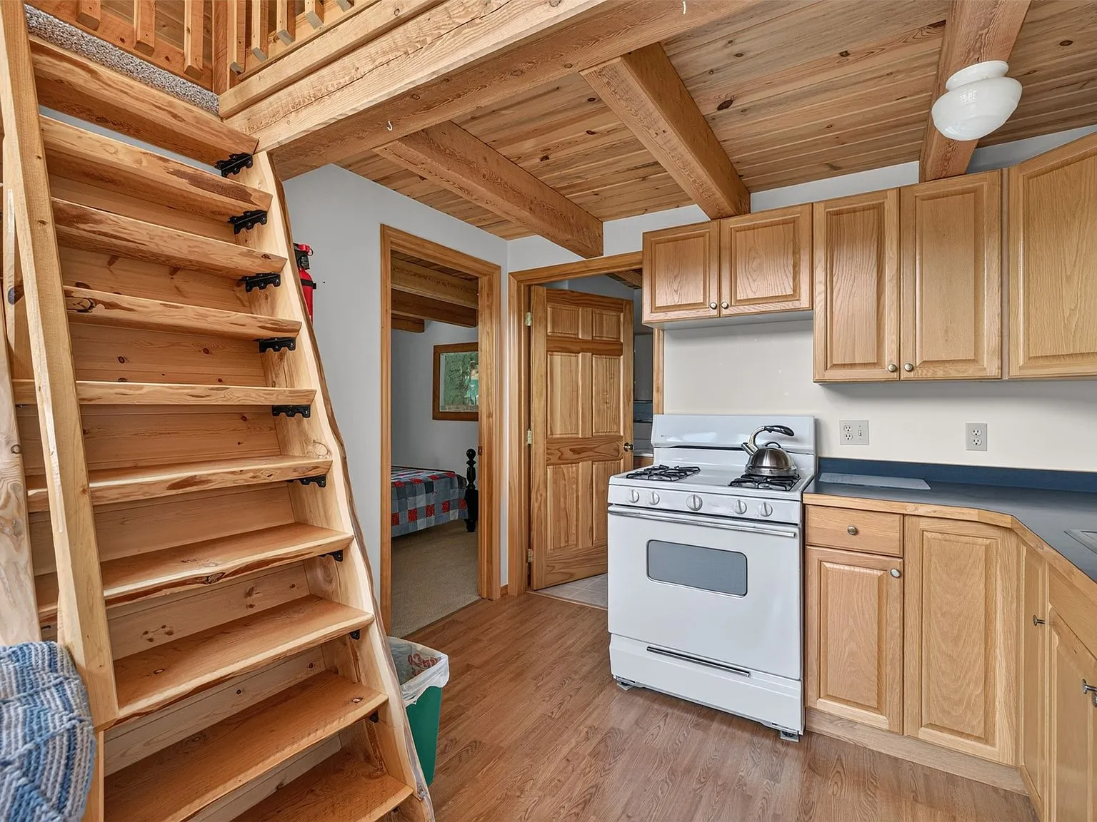 The wood staircase leading up to the loft, with the kitchen visible below