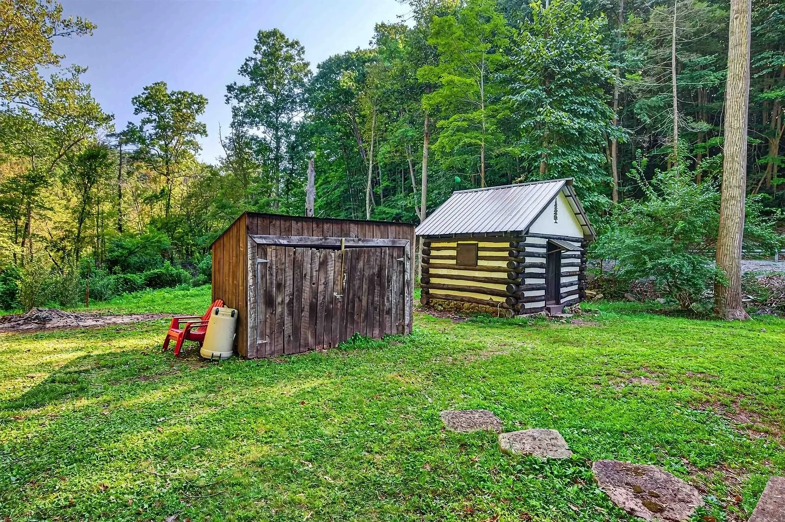 Two log outbuildings at the edge of the trees