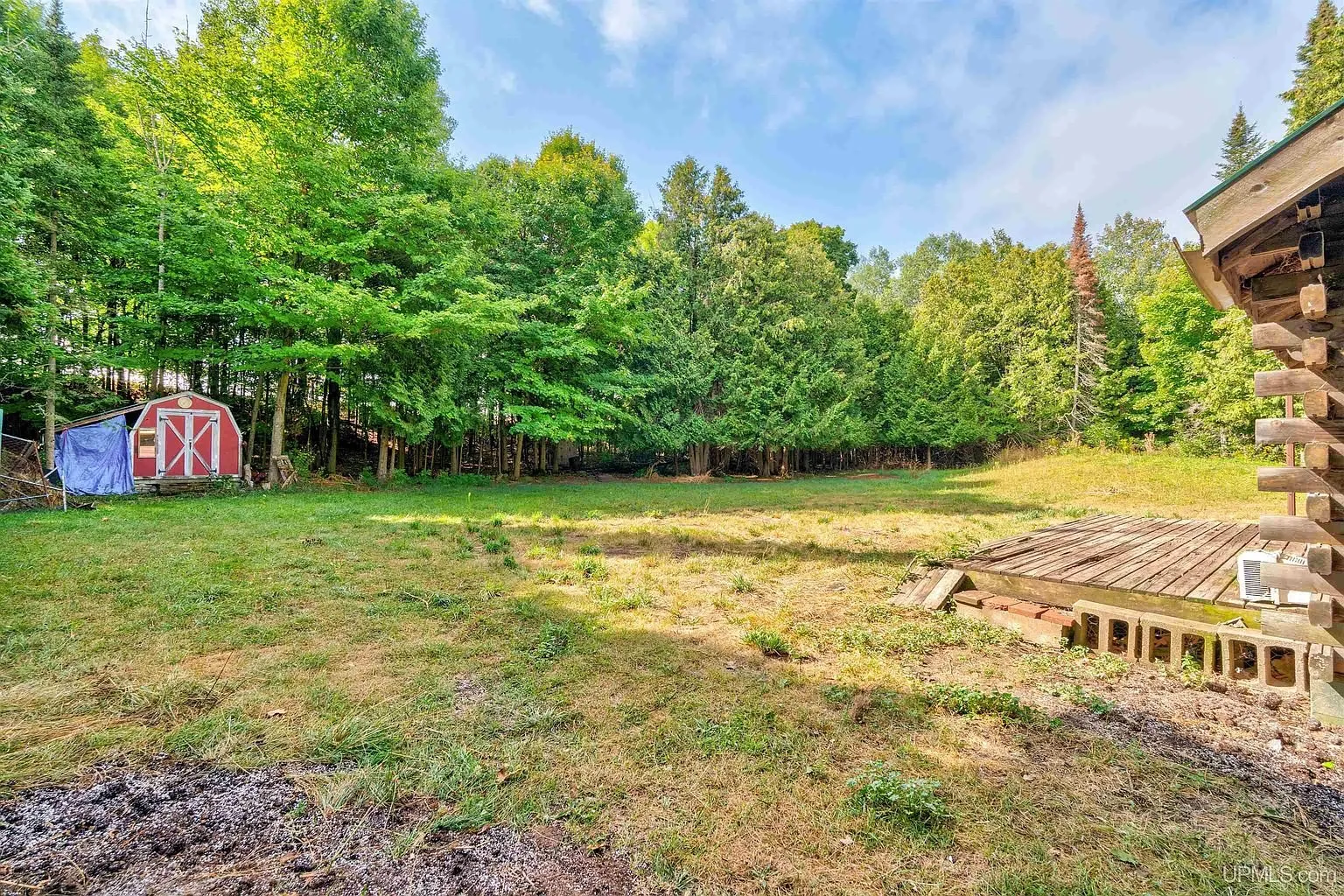 The yard with the red shed, the deck resting on concrete blocks, and a burn pile