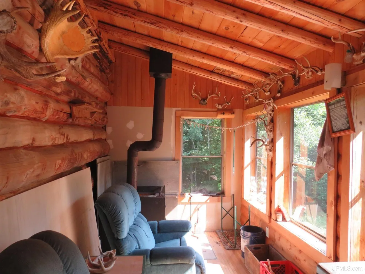 A wood stove in the corner of the main room, pipe running up through the logs