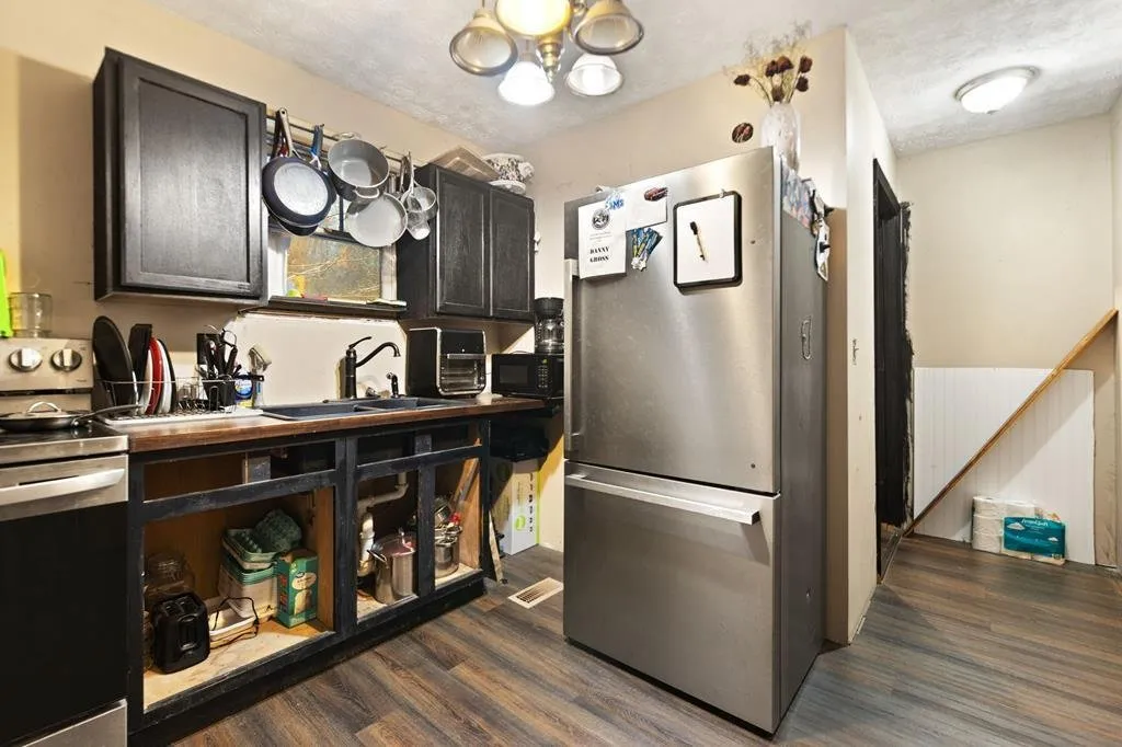Kitchen with dark cabinets, a stainless refrigerator and a window over the sink