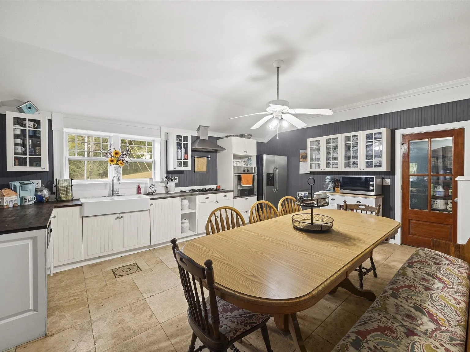 Kitchen and dining area with the farm sink, white cabinets, and tile floor