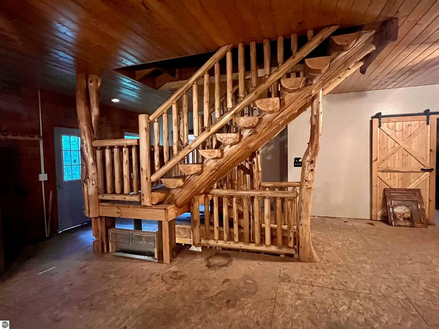 The log stair to the loft with the barn door and the blue door beside it