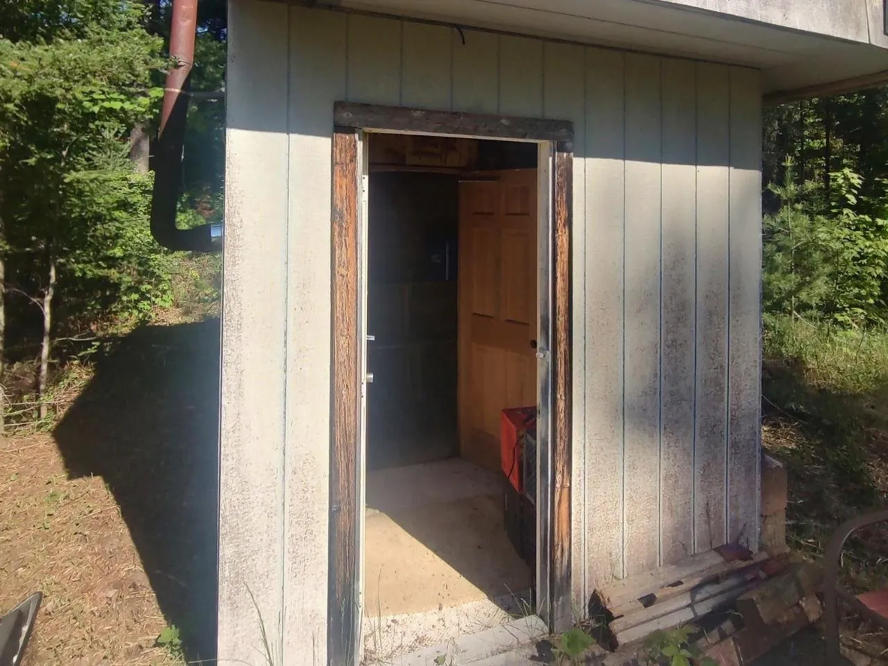 The open door of the sauna building with its stovepipe above