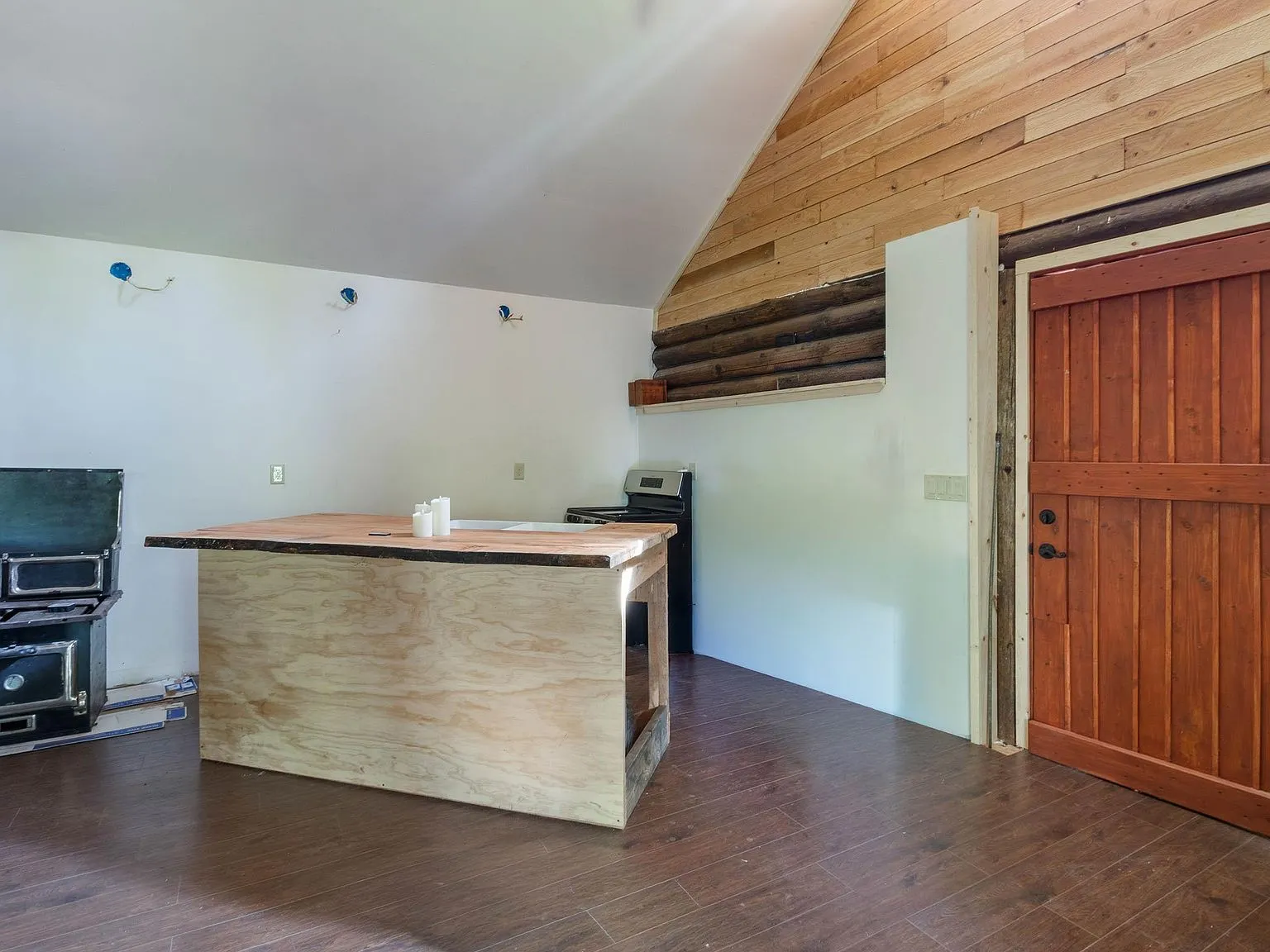 The main room with a sofa, dining table and ladder to the loft, seen from the kitchen area