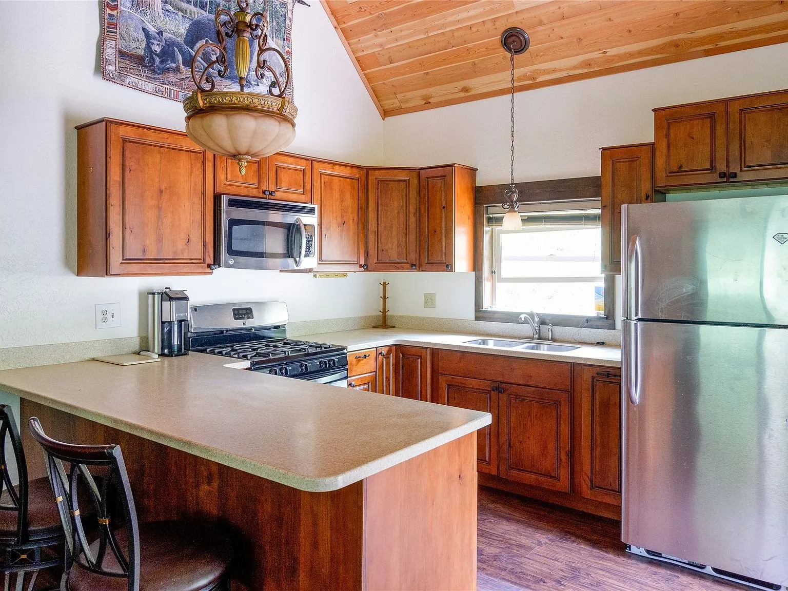 The kitchen's peninsula counter with a gas range and stainless refrigerator