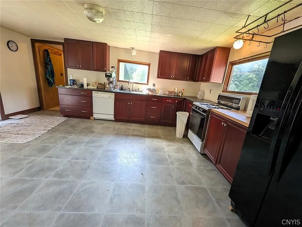 The kitchen from the other end with the door and the black refrigerator