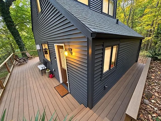 The cabin's front entrance and covered deck, framed by surrounding trees
