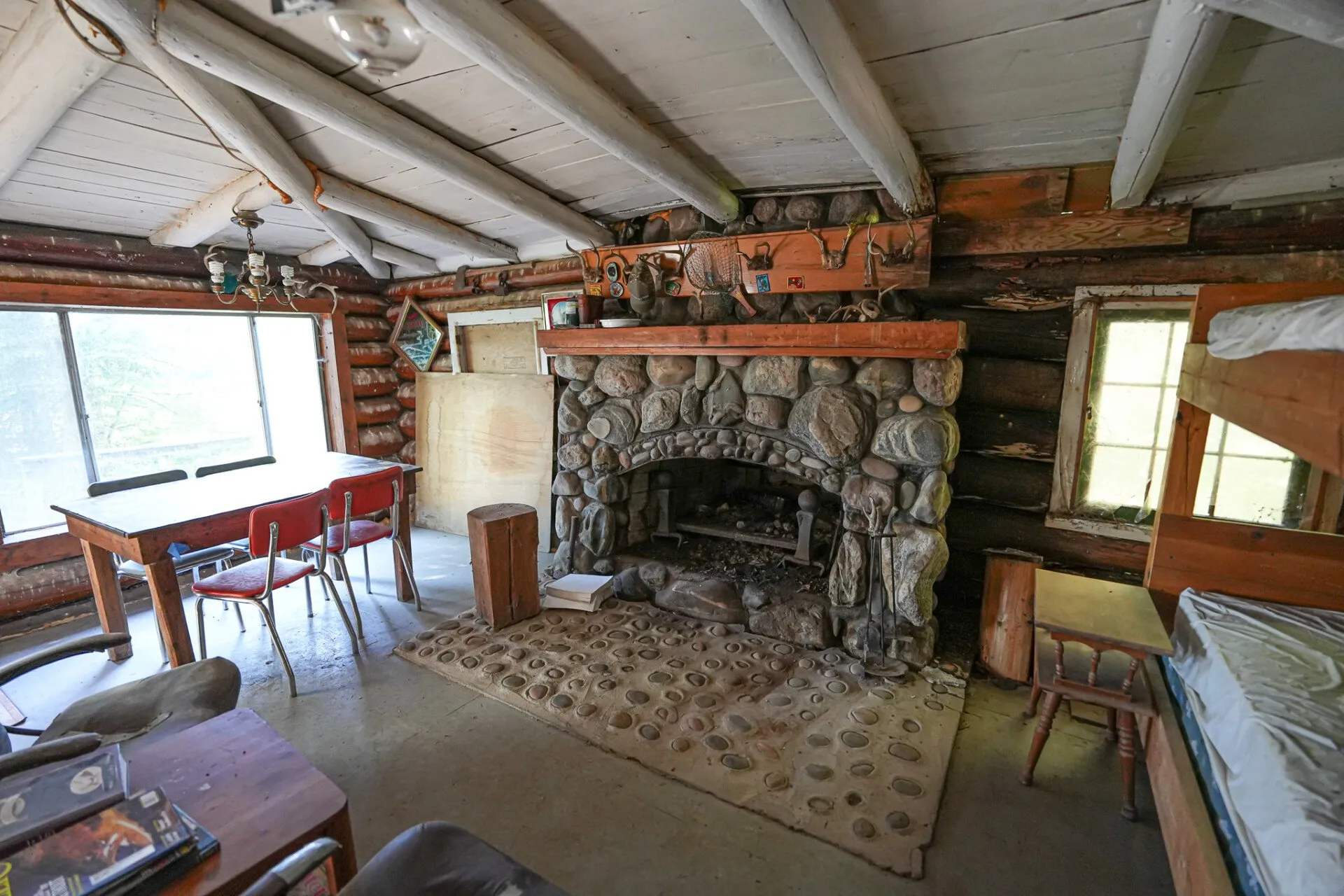 The stone fireplace in the main cabin, chairs pulled up and a rug on the floor
