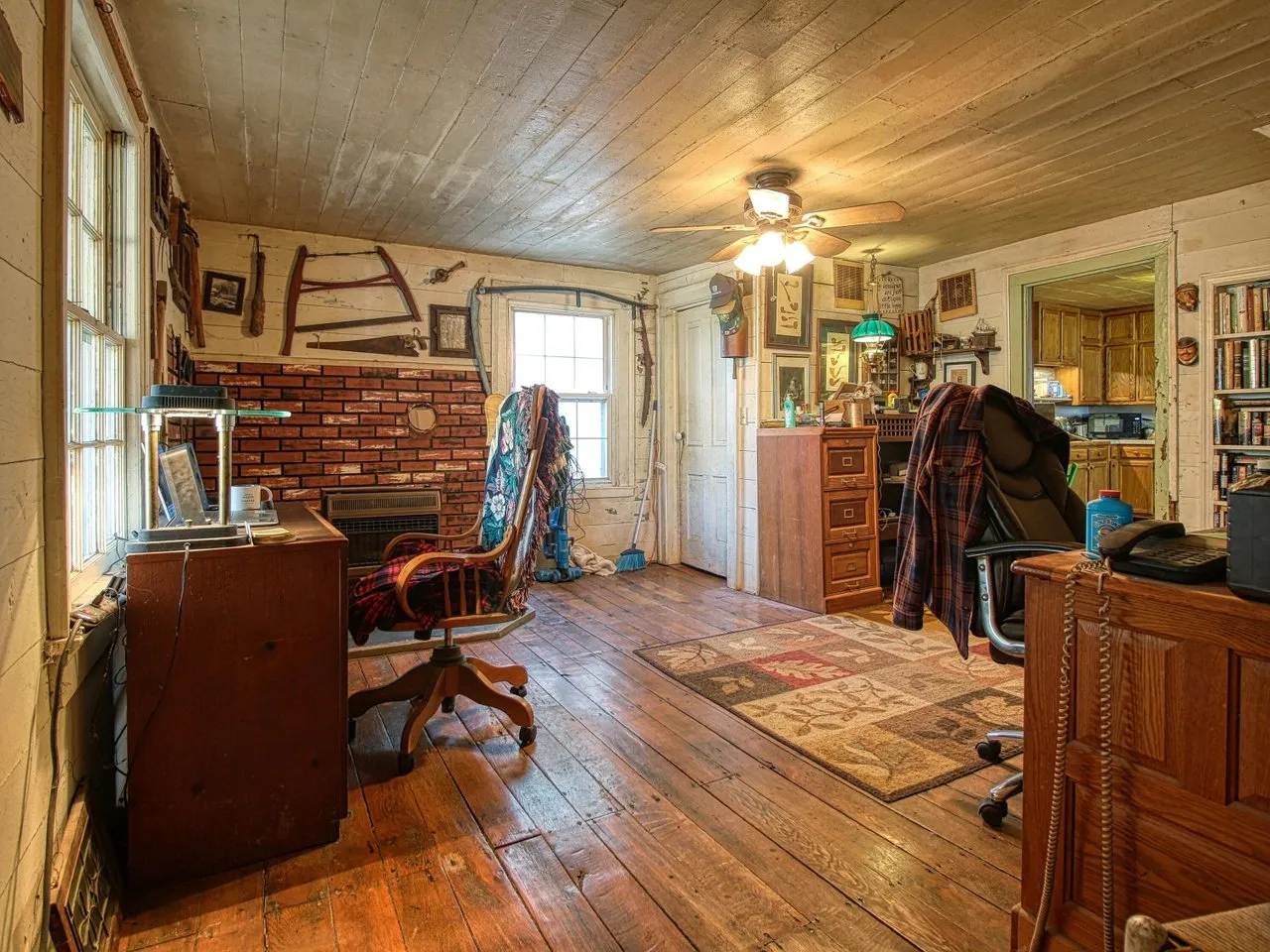 The front room with a brick hearth, a desk and wood floors