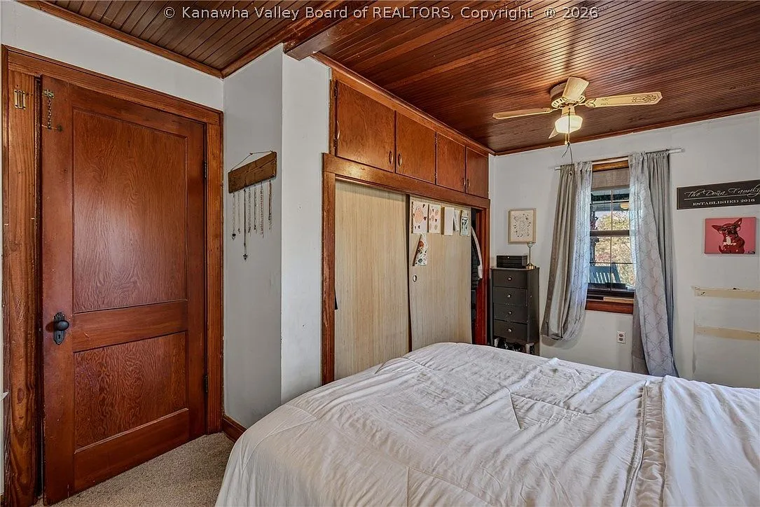 A third upstairs bedroom with dark walls, framed art and a window AC unit