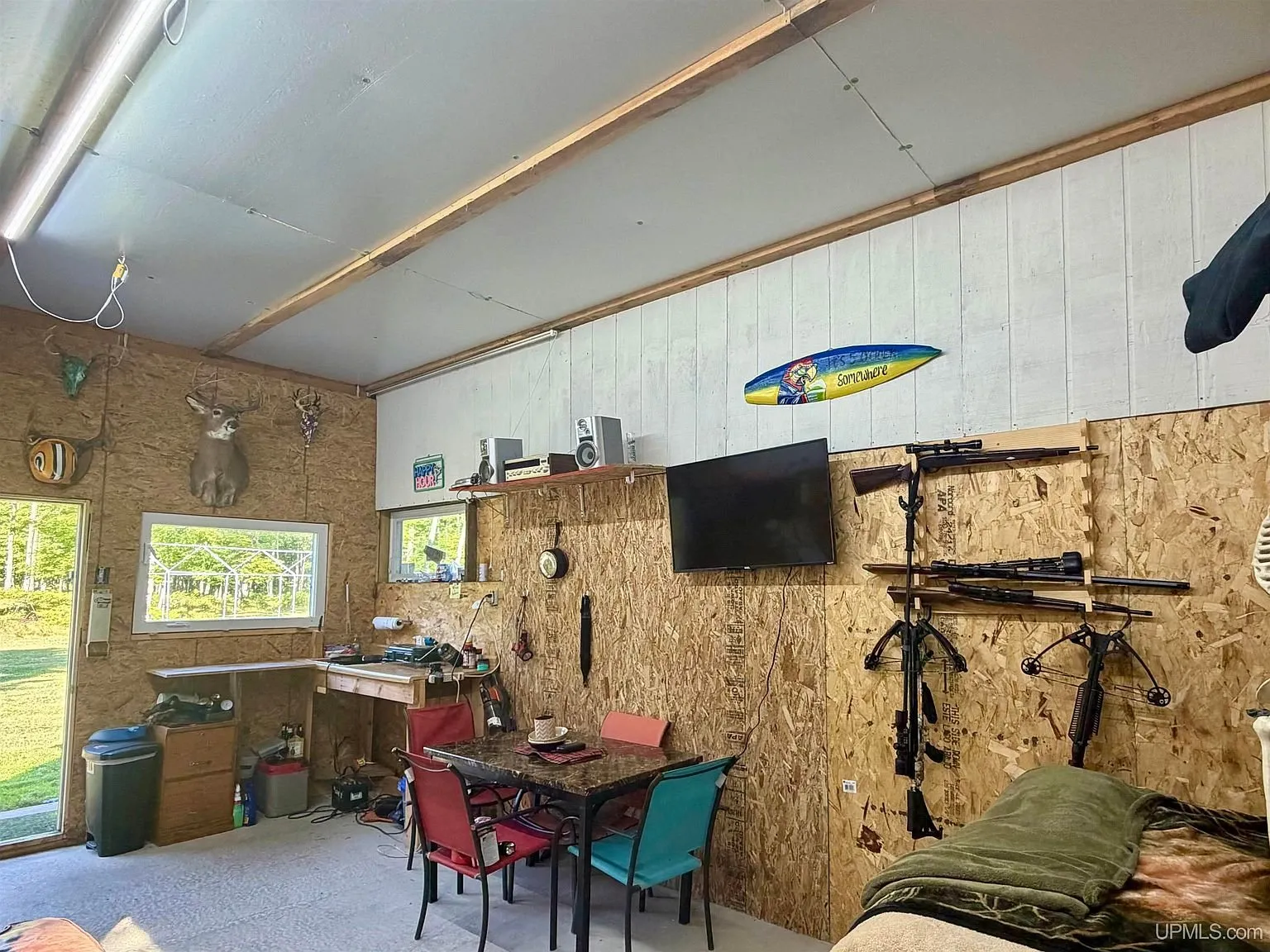 The table in the base camp with the crossbows on the wall and the window onto the yard
