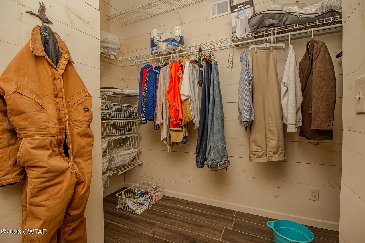 The walk-in closet with hanging rails and shelving on both walls