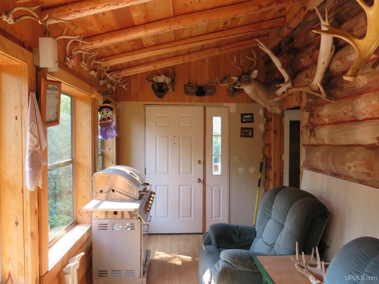 The front door with antlers mounted above it and a recliner beside