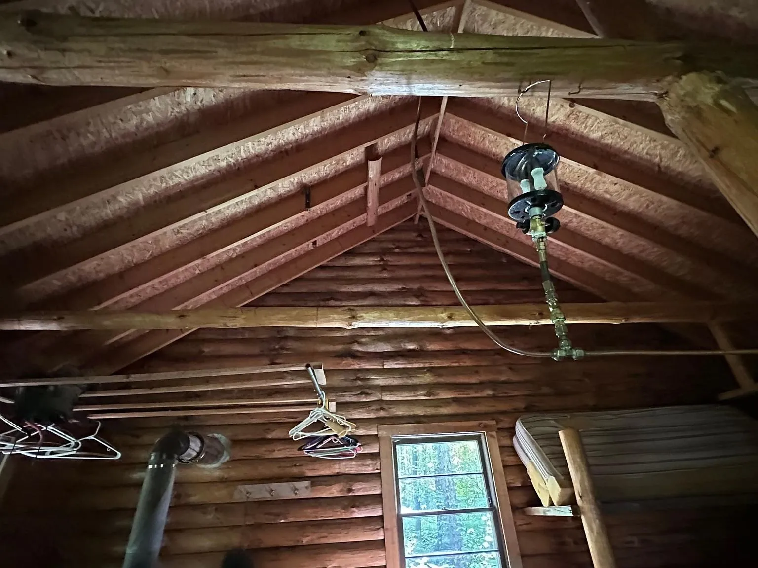 The roof framing overhead with a propane lamp and the built-in bunk