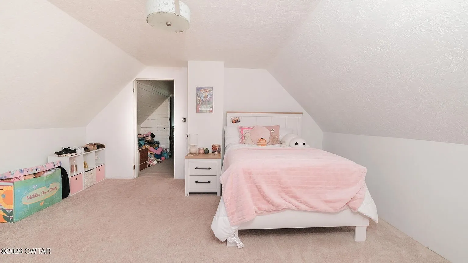 An upstairs bedroom with a single bed and toy bins under the sloped ceiling