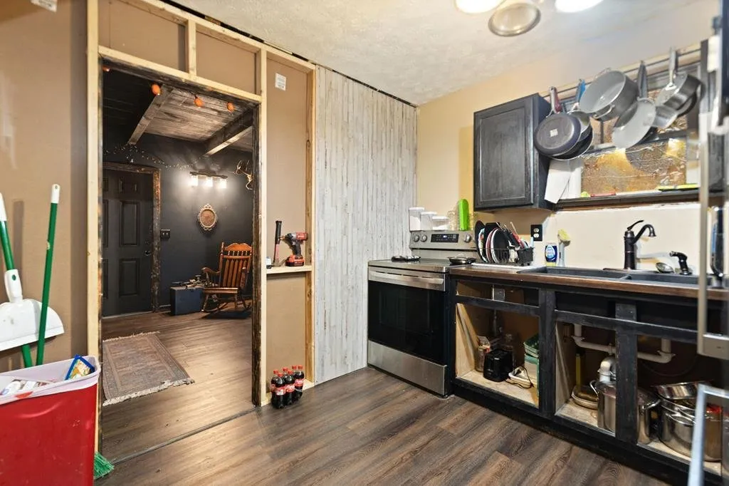 The kitchen counter and range along the wall, stairs beyond