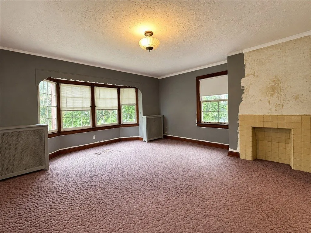 A bedroom with a fireplace, bay windows and radiators