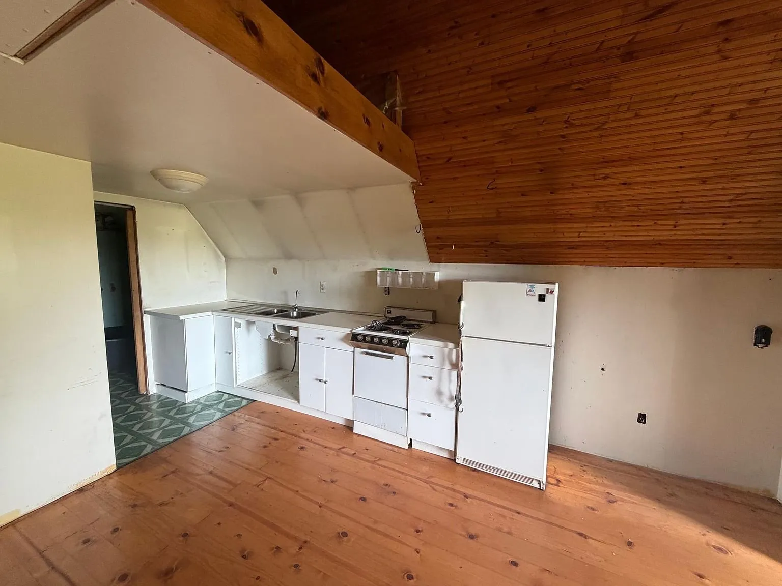 The kitchen corner with the white cabinets, the range and the refrigerator