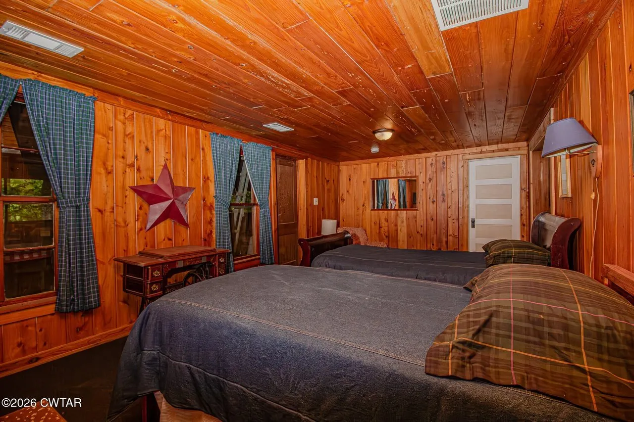 A bedroom with a blue bedspread, wood ceiling and a star on the wall