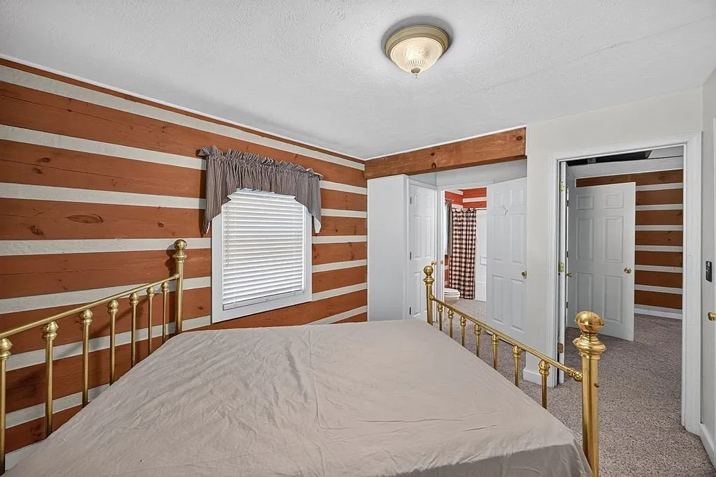 The main-level bedroom with a bed, window and log walls