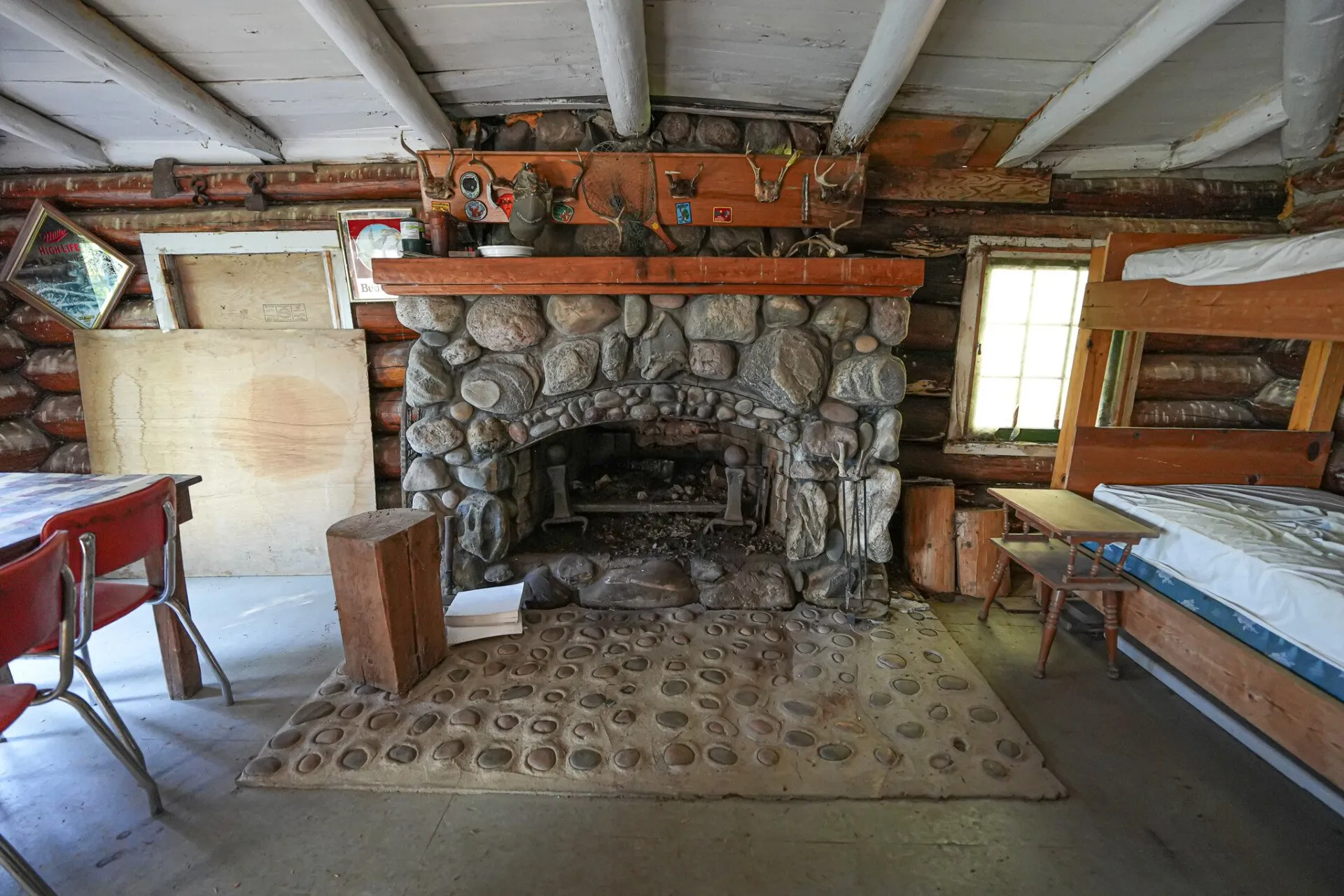 The fireplace end of the cabin with a bunk built into the wall beside it