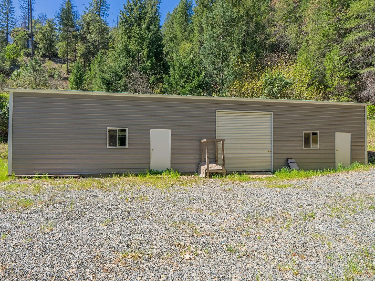 The 60x30 shop building with roll-up doors, seen from the gravel drive