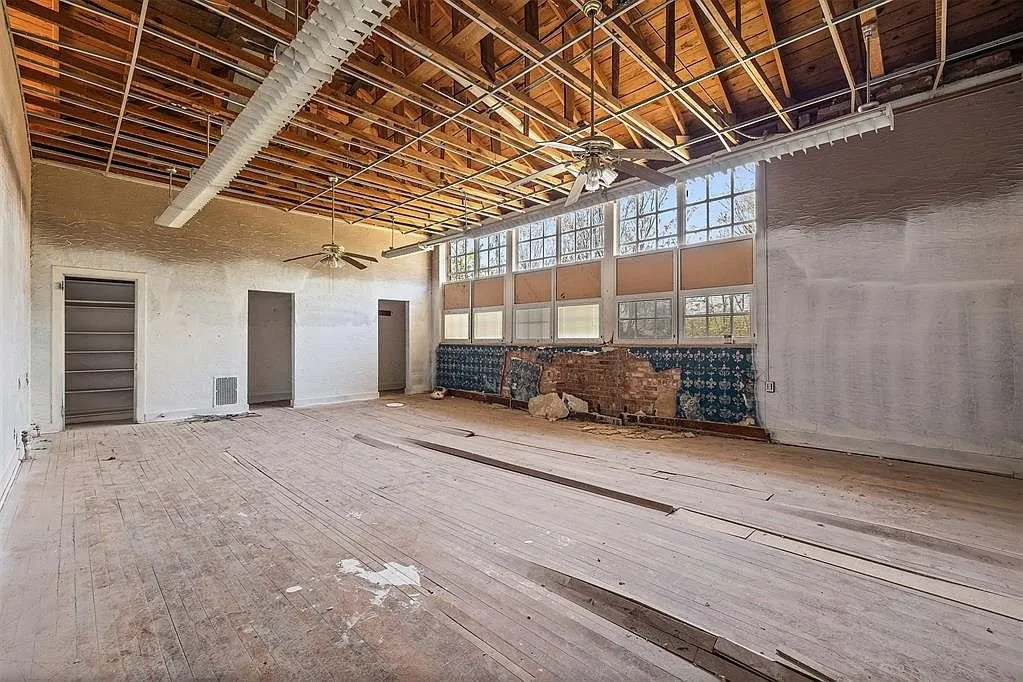 A classroom with the ceiling stripped to the joists and the wall of steel windows